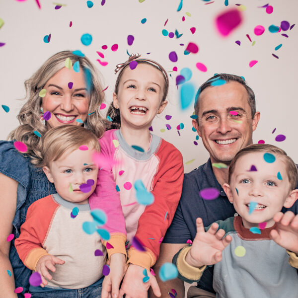 Happy family celebrating with colorful confetti and smiles.