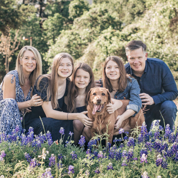 Family of five with their dog in a flower field.